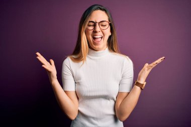 Mor arka plan üzerine gündelik tişört giymiş genç, sarışın bir kadın başarının çılgınlığını kutluyor kollarını kaldırmış, gözlerini kapatmış heyecanlı çığlıklar atıyor. Kazanan konsept