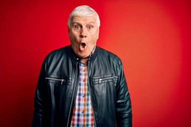 Kıdemli yakışıklı, beyaz gömlekli ve ceketli adam izole edilmiş kırmızı arka plan üzerinde korku dolu ve şaşkınlık dolu bir ifade, korku ve heyecan dolu bir yüz..