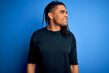 Rastgele tişörtler giyen Afro-Amerikan Afro-Amerikan genç adam yüzünde gülümseme ve doğal bir ifadeyle diğer tarafa bakıyor. Kendinden emin gülen.