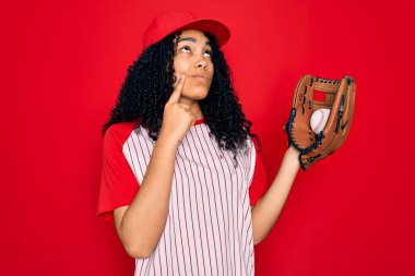 Genç Afro-Amerikan kıvırcık saçlı şapkalı sporcu beysbol oynuyor. Top ve eldiven kullanıyor. Ciddi bir yüz ifadesi var.