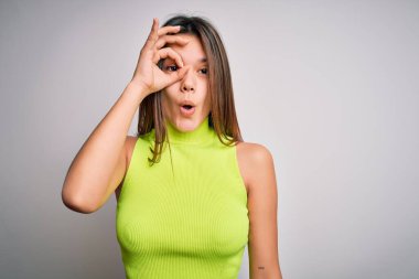 Genç, güzel esmer kız izole edilmiş beyaz arka plan üzerine günlük tişört giyiyor. Şaşırmış yüz ifadesiyle şaşırmış, parmaklarından bakan gözler. İnançsız ifade.