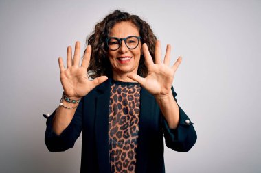 Orta yaşlı esmer iş kadını gözlüklü, izole edilmiş beyaz arka planda duran ve parmaklarını on numara gösteren kendinden emin ve mutlu bir şekilde gülümseyen..