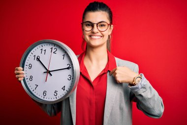 Genç ve güzel esmer iş kadını geri sayım yapıyor. Elinde koca bir saat var.