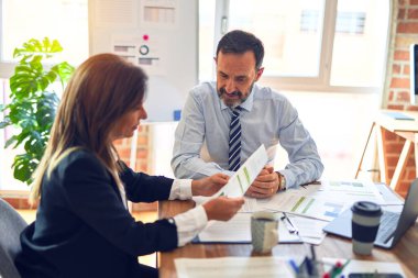 Mutlu ve kendinden emin gülümseyen iki orta yaşlı iş adamı. Ofiste dizüstü bilgisayarla gülümseyerek birlikte çalışıyoruz.