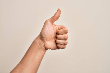 Beyaz arka planda parmaklarını gösteren beyaz tenli bir gencin eli başarılı bir onay hareketi yapıyor. Başparmak işareti, onay ve olumlu bir sembol ile.