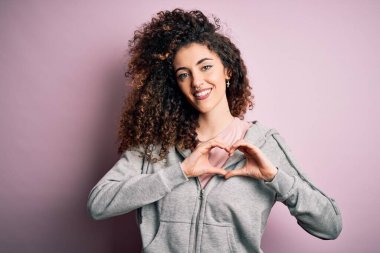 Kıvırcık saçlı ve piercingli genç ve güzel esmer kadın. Spor giyiniyor. Sevgiyle gülümsüyor. Romantik konsept.