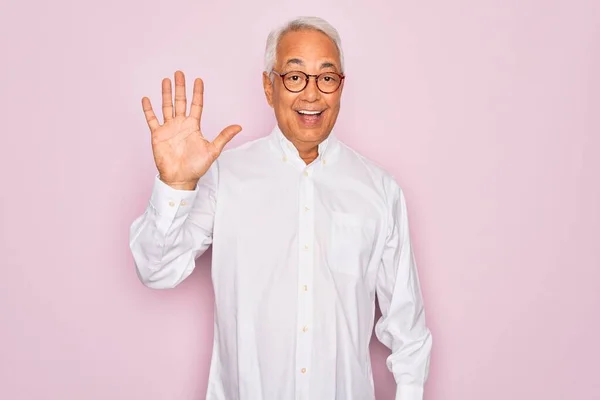 中年シニア白髪男身に着けている眼鏡とビジネスシャツ上ピンクの背景表示と指差しで指番号5ながら笑顔自信と幸せ — ストック写真