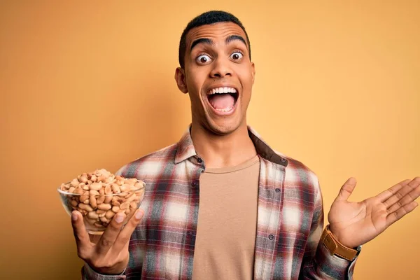 Handsome African American Man Holding Bowl Heathy Peanuts Yellow Background — Stock Photo, Image