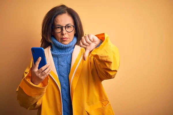 Middelbare Leeftijd Vrouw Dragen Gele Regenjas Met Behulp Van Smartphone — Stockfoto