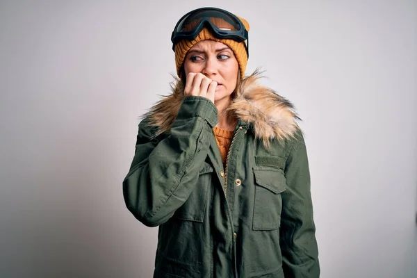 年轻美丽的滑雪者女人 蓝眼睛 身穿雪地运动服和滑雪护目镜 双手放在咬指甲的嘴上 看起来很紧张 很紧张 焦虑问题 — 图库照片