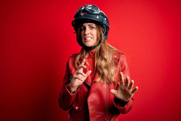 赤の背景で元ヘルメットをかぶっている若い美しいブルネットのオートバイの女性は嫌悪反応のために嫌悪感の表情 不満で恐ろしい嫌悪感の表情をしている 手を挙げて — ストック写真