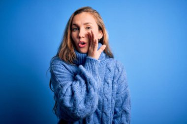 Mavi arka plan üzerine balıkçı yaka kazak giyen genç, güzel sarışın kadın gizli dedikodular söylüyor, kötü niyetli konuşmalar fısıldıyor.