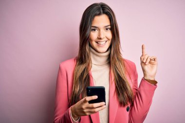 Genç güzel bir kız beyaz arka plan üzerinde akıllı telefon kullanarak konuşuyor. Bir fikir ya da soru işareti ile şaşırmış, mutlu bir yüz, bir numara.