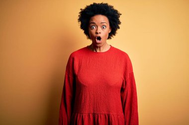 Young beautiful African American afro woman with curly hair wearing casual sweater afraid and shocked with surprise expression, fear and excited face.