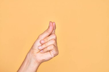 İzole edilmiş sarı arka planda parmaklarını gösteren beyaz bir adamın eli. Parmak, iş ve reklamla boş bir alan tutuyor.