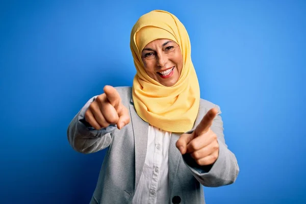 中年黑发女商人头戴穆斯林传统头巾 头戴蓝色背景 手指指向你和相机 面带微笑 面带微笑 面带微笑 — 图库照片