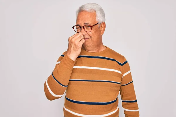 中世の高齢者の白髪のハンサムな男が眼鏡とカジュアルな縞模様のセーターを着て鼻の上に指で息を保持し 臭いと嫌な 耐え難い匂い何かを嗅ぐ 匂いが悪い — ストック写真