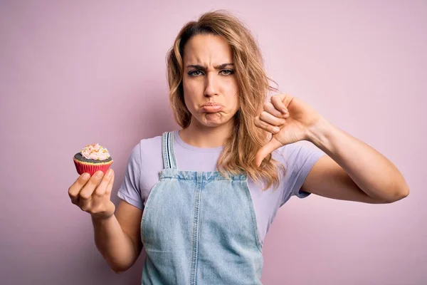 Fiatal Gyönyörű Szőke Eszik Csokoládé Cupcake Felett Elszigetelt Rózsaszín Háttér — Stock Fotó
