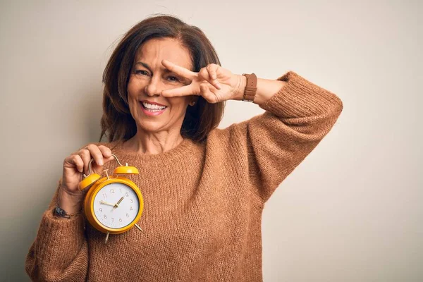 Brunetka Średnim Wieku Kobieta Trzyma Klasyczny Budzik Odosobnionym Tle Robi — Zdjęcie stockowe