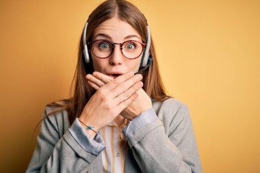 Genç kızıl saçlı çağrı merkezi ajanı kadın gözlük takarak çok çalışıyor kulaklık takıyor ağzı yanlışlıkla ellerle kapatıyor. Gizli konsept.