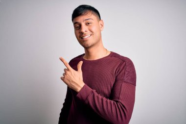 Genç, yakışıklı, İspanyol gömlekli, beyaz, izole edilmiş arka planda duran neşeli yüzlü, yüzünde mutlu ve doğal bir ifadeyle el ve parmaklarıyla gülümseyen bir adam.