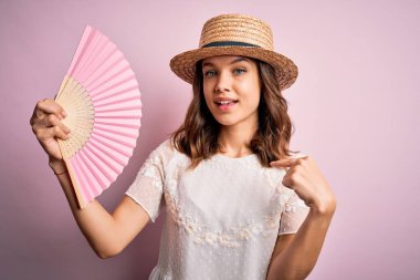 Genç sarışın moda kızı sıcak bir yaz gününde ahşap ispanyolca el yelpazesi kullanıyor.