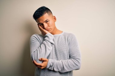 Genç, yakışıklı, latin bir adam. Sıradan bir süveter giyiyor. İzole edilmiş beyaz arka plan üzerinde duruyor..