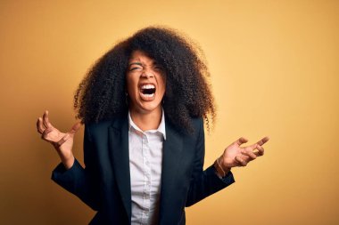 Afro saçlı, şık ceketli, deli gibi bağıran, agresif ifade ve kollarıyla bağıran güzel Afro-Amerikan iş kadını. Hayal kırıklığı konsepti.