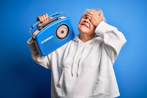Senior Mooie Vrouw Met Vintage Radio Staande Geïsoleerde Blauwe Achtergrond — Stockfoto