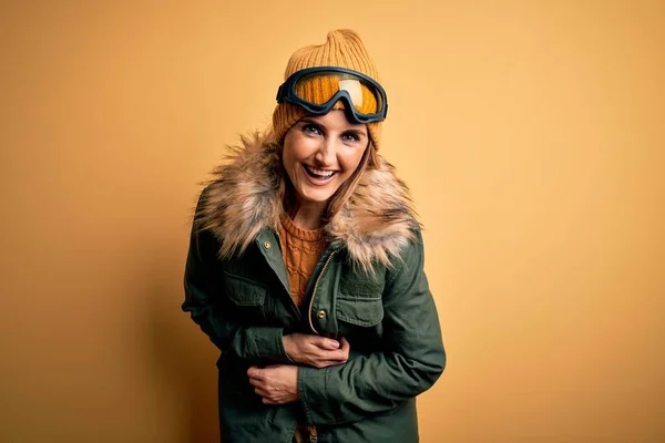 中年美丽的金发滑雪者女人穿着雪地运动鞋 戴着雪地护目镜 笑着大声笑着 因为一个可笑的疯狂笑话 双手放在身上 — 图库照片