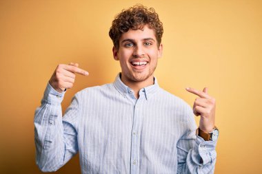 Sarışın, kıvırcık saçlı, sarı arka planda çizgili gömlek giyen, kendine güvenen, kendini gururlu ve mutlu gösteren genç bir adam..