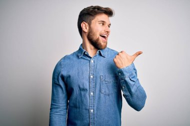 Sakallı, mavi gözlü, sıradan bir kot gömlek giyen mutlu yüzüyle gülümseyen ve baş parmağıyla yüzünü gösteren genç, yakışıklı sarışın bir adam..