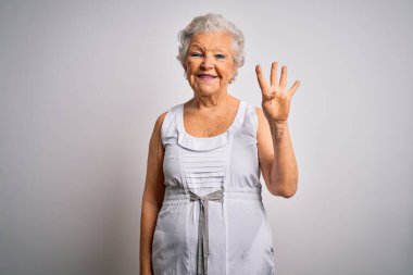 Son sınıf güzeli, gri saçlı kadın beyaz arka plan üzerine yazlık elbiseler giyiyor ve parmaklarını dört numarayı göstererek gülümsüyor ve mutlu..