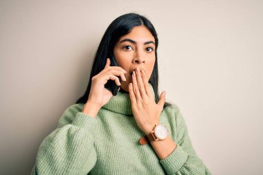 Genç ve güzel İspanyol bir kadın akıllı telefondan konuşuyor. Ağzı kapalı konuşuyor. Utanç verici bir hata, korku ifadesi, sessizlikten korkmak, gizli bir konsept.