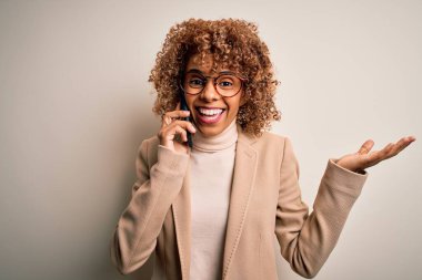 Kıvırcık saçlı genç Afrikalı Amerikalı kadın akıllı telefonda konuşuyor. Çok mutlu ve heyecanlı. Kazanan ifade zaferi büyük bir gülümsemeyle kutluyor ve ellerini kaldırıyor.