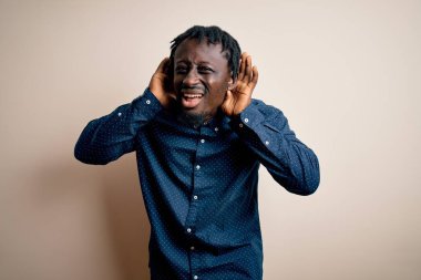 Beyaz arka plan üzerinde dikilmiş, dedikodu meraklısı genç ve yakışıklı Afro-Amerikalı adam iki elini de kulak hareketlerini duymaya çalışıyor. İşitme problemi, sağır