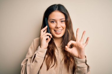 Genç, güzel esmer kadın akıllı telefonda konuşuyor. Parmaklarıyla imza atıyor. Mükemmel bir sembol.