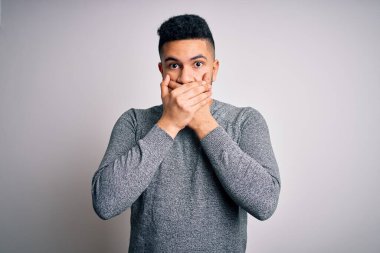 Young handsome man wearing casual sweater standing over isolated white background shocked covering mouth with hands for mistake. Secret concept.