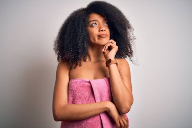 Afro saçlı Afrikalı genç bir kadın güzellik öncesi duştan sonra el pençe divan durup soru soran, düşünceli bir ifade takınıyor. Düşünceli bir yüzle gülümsüyor. Şüphe kavramı.