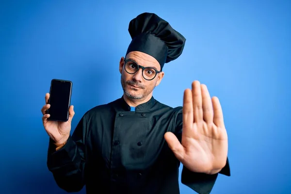Joven Hombre Guapo Chef Con Uniforme Sombrero Sosteniendo Teléfono Inteligente —  Fotos de Stock