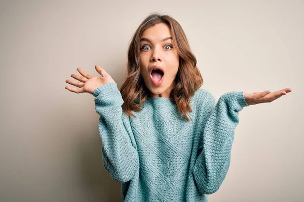 Sarışın bir genç kız, izole edilmiş arka planda sıradan mavi bir kazak giyip kollarını kaldırıp heyecanla haykırarak çılgın ve başarıyı kutluyor. Kazanan konsept