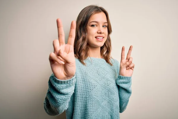 파란색의 스웨터를 소녀는 카메라 앞에서 손가락 승리의 표시를 — 스톡 사진