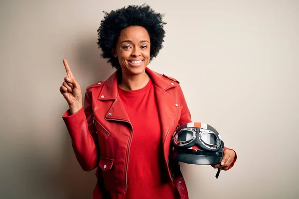 年轻的非洲裔美国骑摩托车的妇女 手持摩托车头盔 脸上挂着大大的笑容 手指头指向侧面看相机 — 图库照片