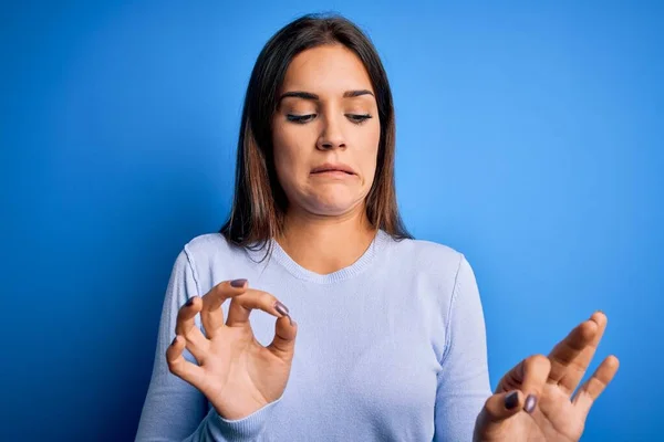 stock image Young beautiful brunette woman wearing casual sweater standing over blue background disgusted expression, displeased and fearful doing disgust face because aversion reaction.