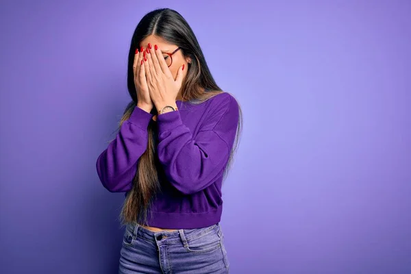 Young beautiful smart woman wearing glasses over purple isolated background with sad expression covering face with hands while crying. Depression concept.