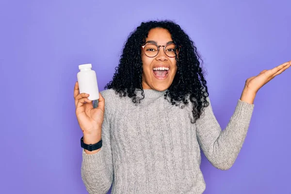 Jovem Afro Americana Encaracolado Mulher Segurando Pílulas Sobre Fundo Roxo — Fotografia de Stock