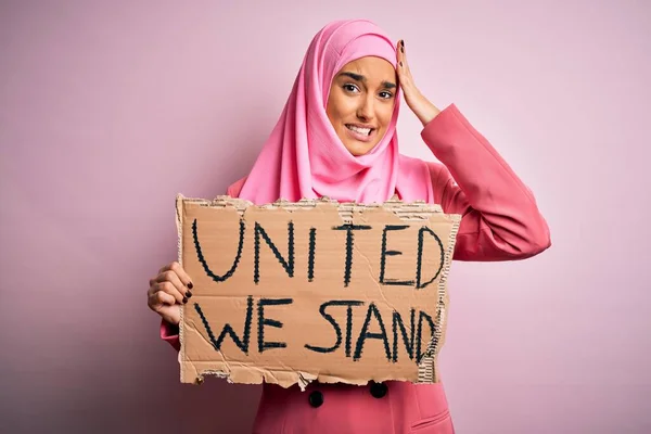 ピンクのイスラム教徒のヒジャーブを身に着けている若い活動家の女性が団結してバナーを保持我々の頭の上に手で強調メッセージを立って 恥と驚きの顔で 怒っていると不満ショックを受けた 恐怖と過ちへの動揺 — ストック写真