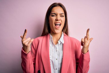 Güzel, esmer, ceketli bir kadın izole edilmiş pembe arka planda duruyor çılgın bir ifadeyle elleri havada rock sembolü yapıyor diye bağırıyor. Müzik yıldızı. Ağır konsept.
