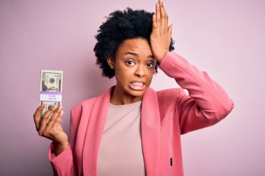 Saçları kıvırcık kıvırcık saçlı, banknotlar tutan genç Afrikalı afro iş kadını. Elleri başının üstünde, utanç ve şaşkınlık dolu, sinirli ve hayal kırıklığına uğramış bir halde. Hata için korku ve üzüntü.