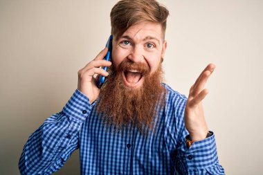Kızıl saçlı, sakallı İrlandalı bir adam akıllı telefondan konuşuyor. Arka planda çok mutlu ve heyecanlı. Kazanan yüz ifadesi zaferi kutluyor.
